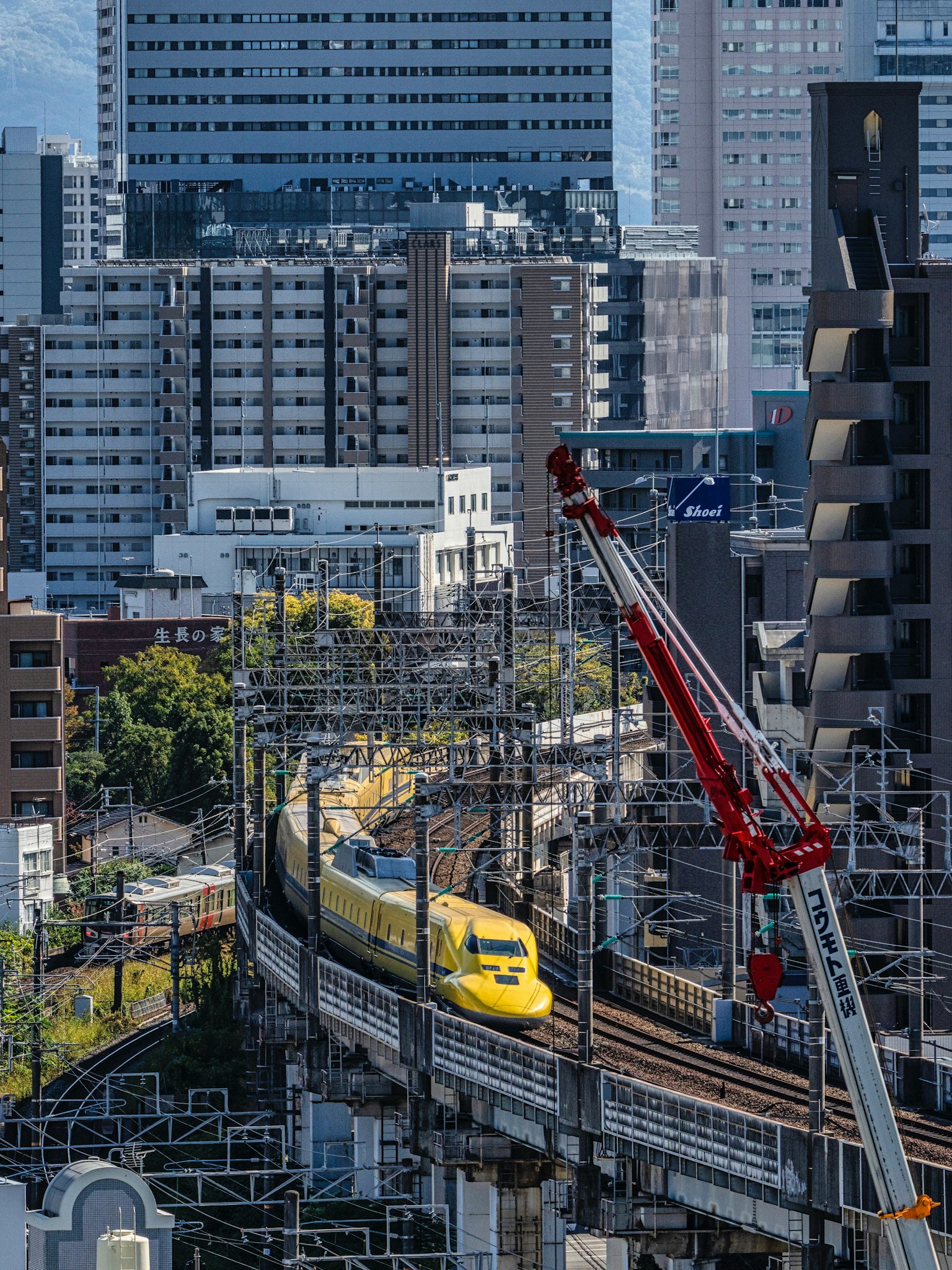 都市の中を走る新幹線の黄色い列車と周囲の高層ビル