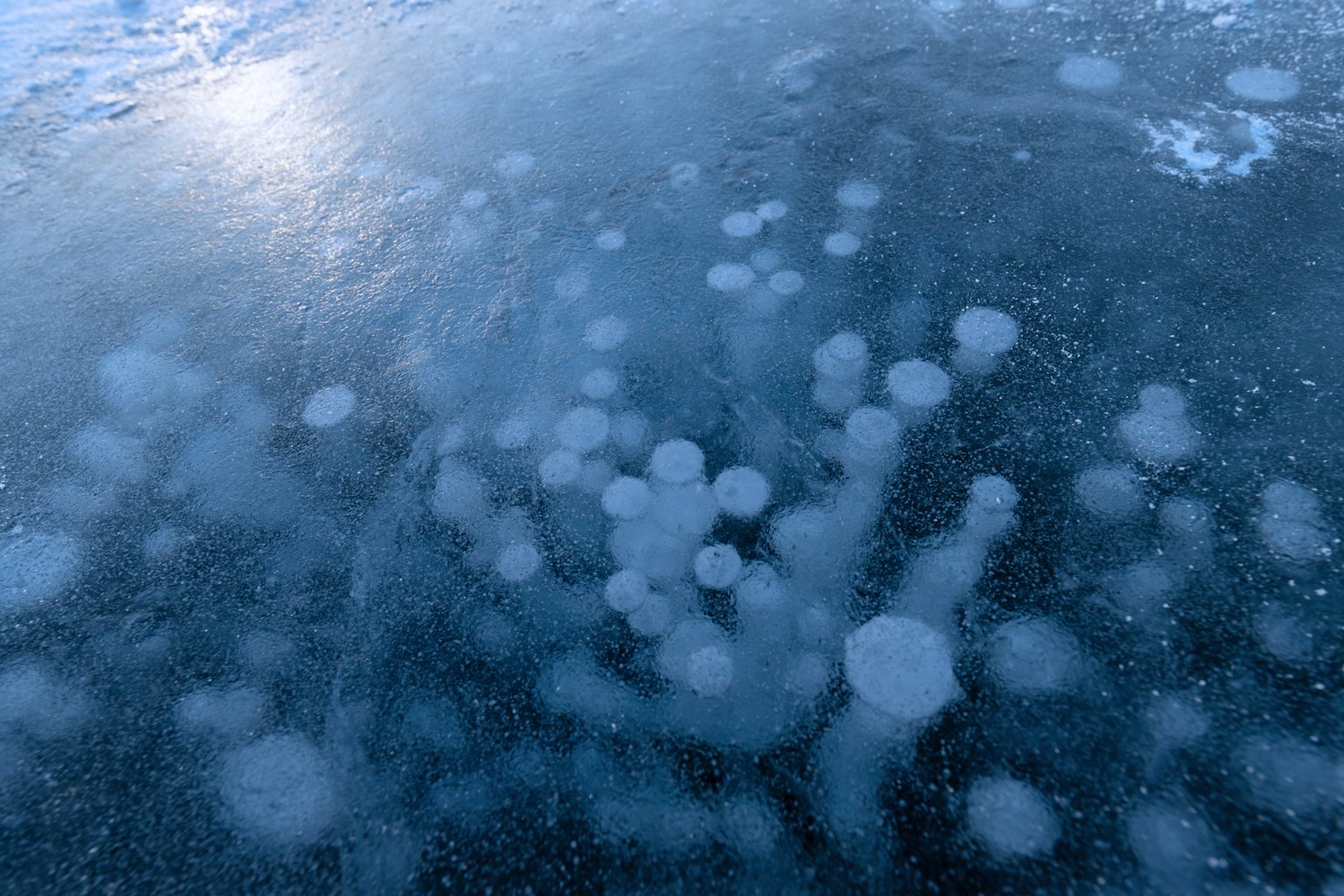 Bulles piégées sous la glace, surface de glace bleue, beauté naturelle