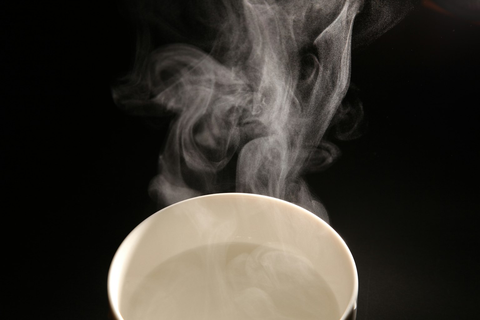 白色杯子上方升起蒸汽的透明水