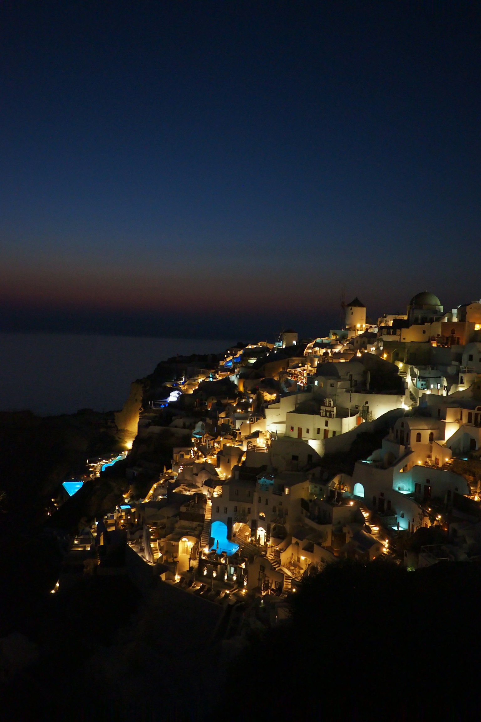 Hermosa vista nocturna de Santorini con edificios iluminados y mar azul