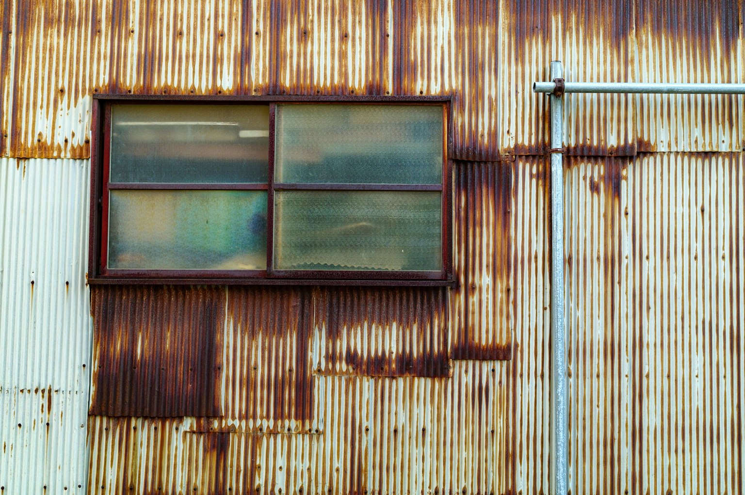Exterior of a factory with a window on a rusty metal wall
