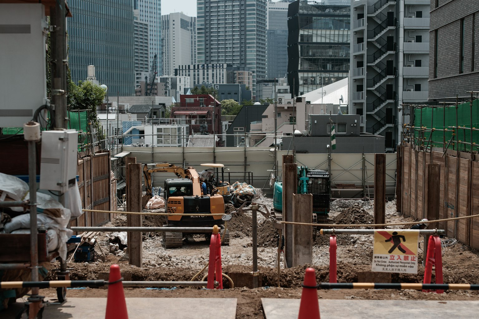 Sitio de construcción con maquinaria pesada y skyline urbano al fondo