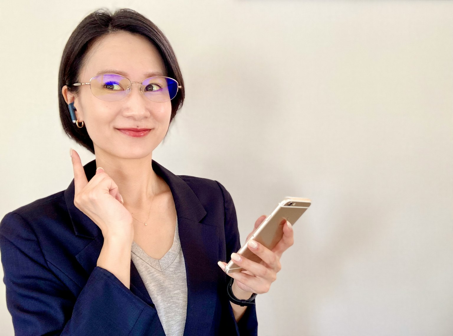 微笑的女性商业人士手持智能手机佩戴蓝色框眼镜