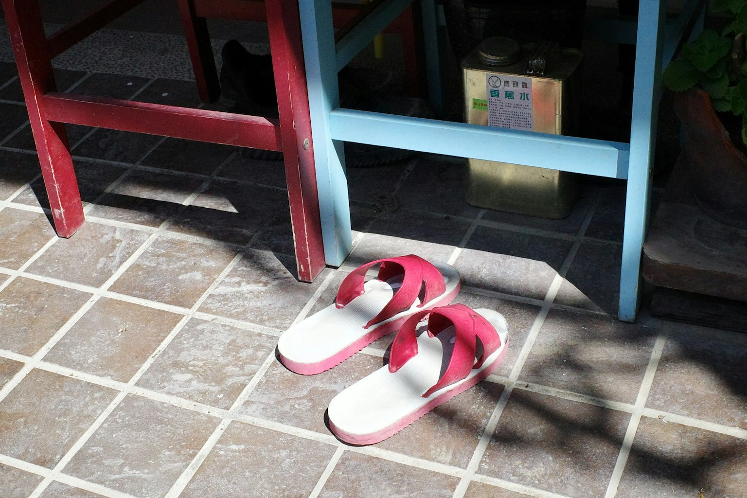 赤いサンダルが青い椅子の下に置かれているタイルの床