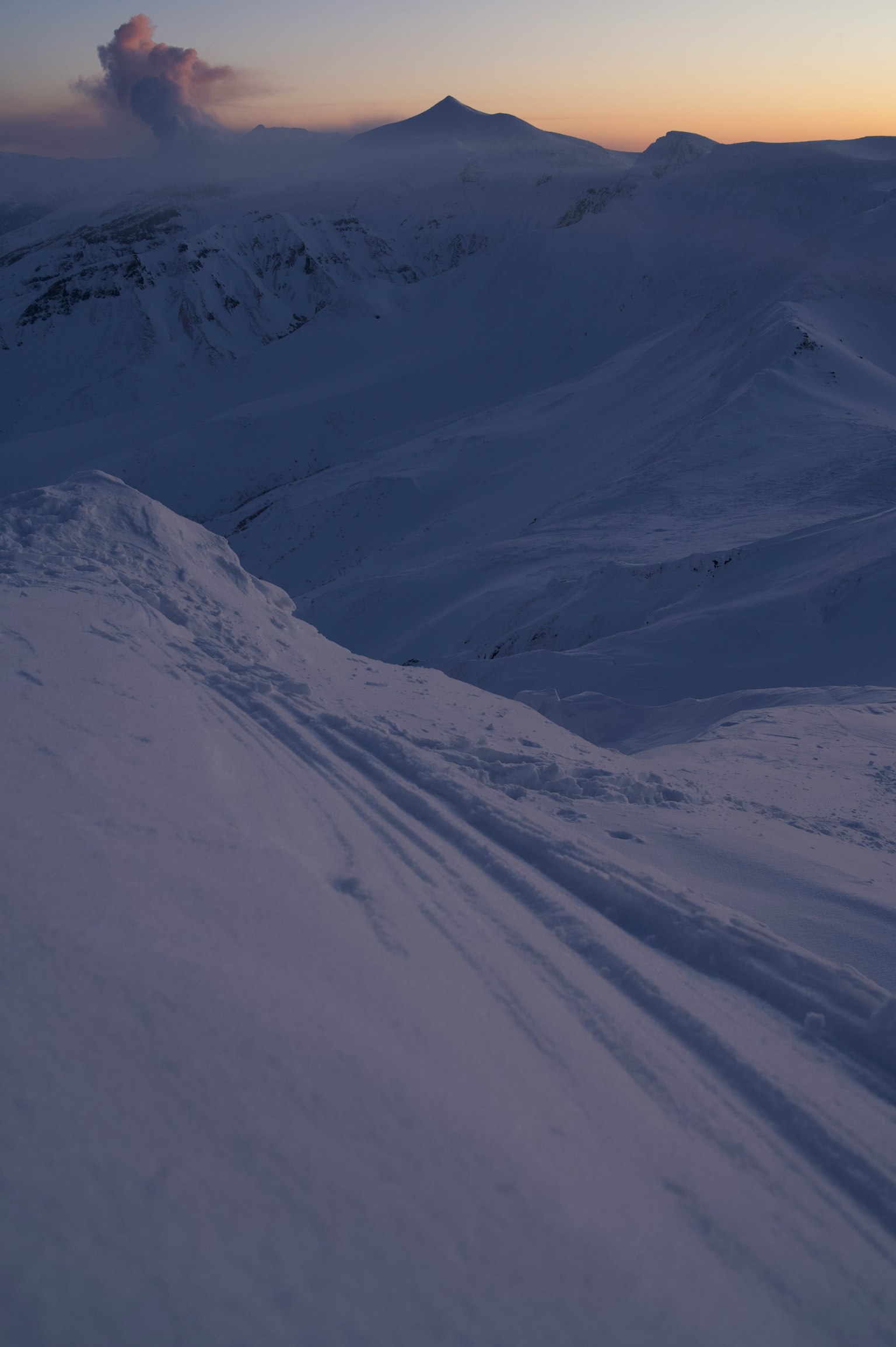 Snow-covered mountain landscape with sunset sky