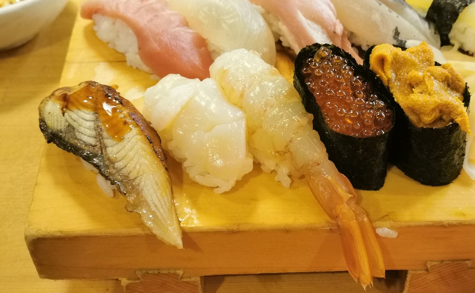 ซูชิหลากหลายชนิดบนจานไม้รวมถึงกุ้งและปลา