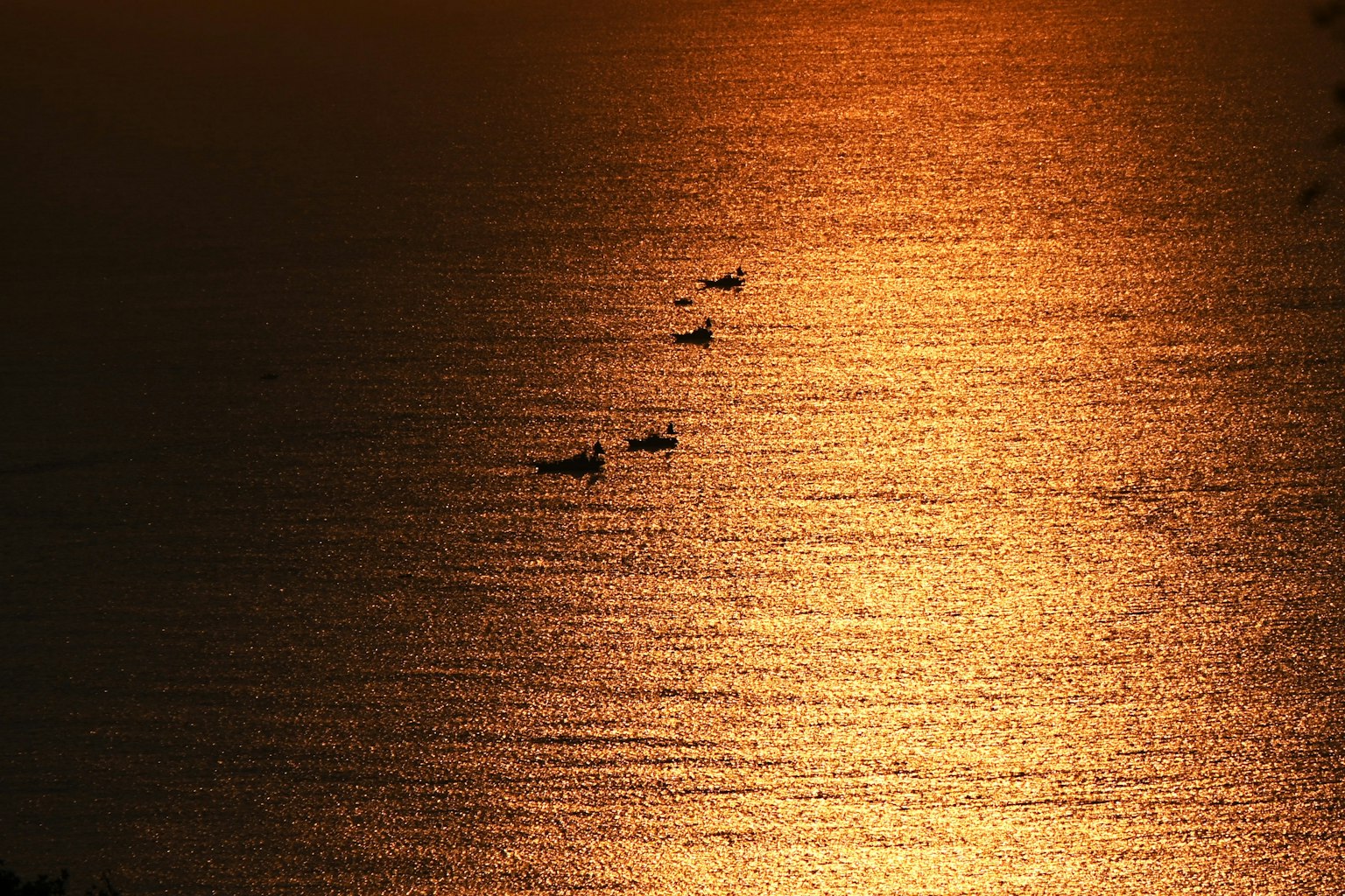Bellissimo paesaggio con piccole barche su una superficie marina che riflette il tramonto
