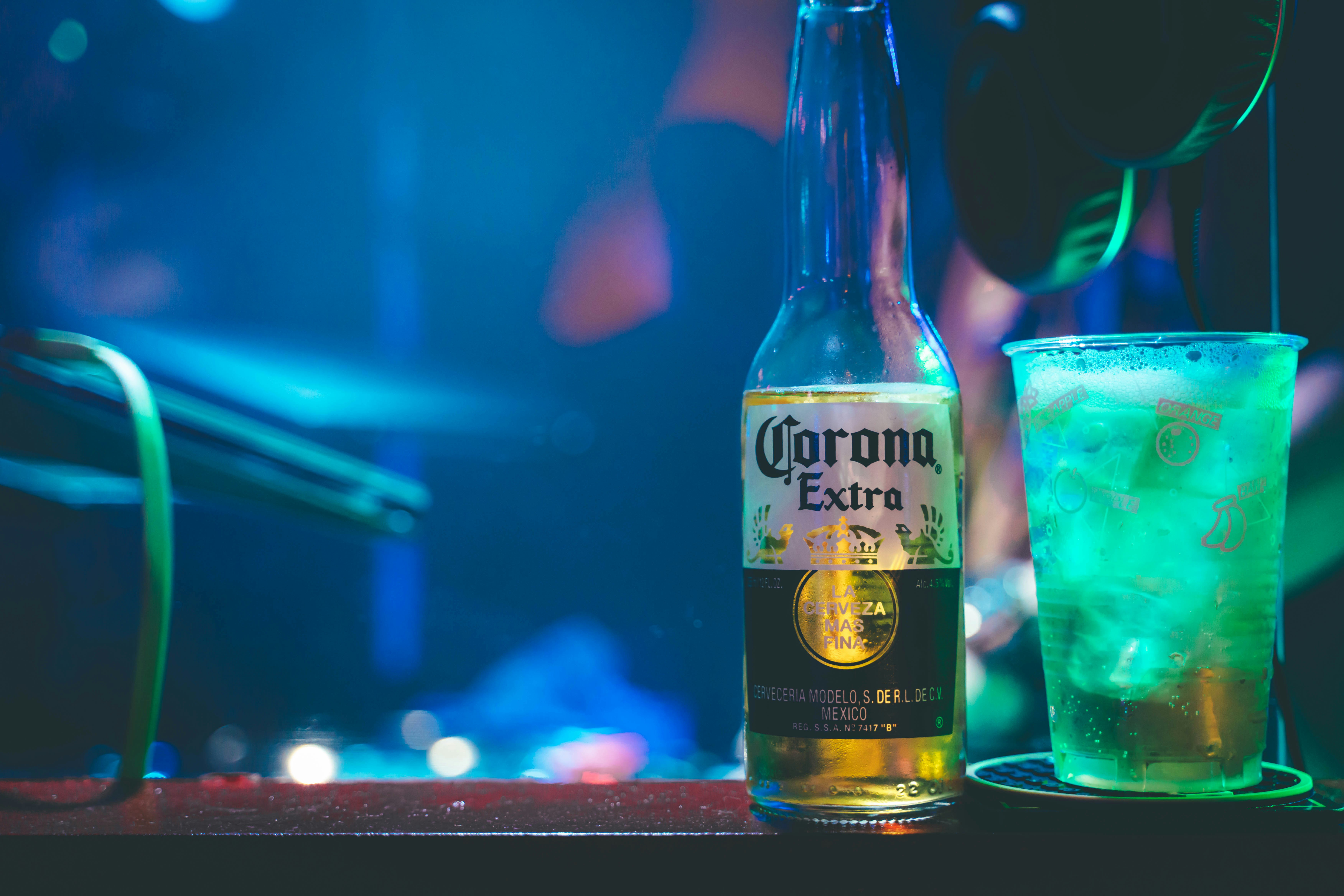 botella de cerveza y vaso de cóctel en una barra con neón azul