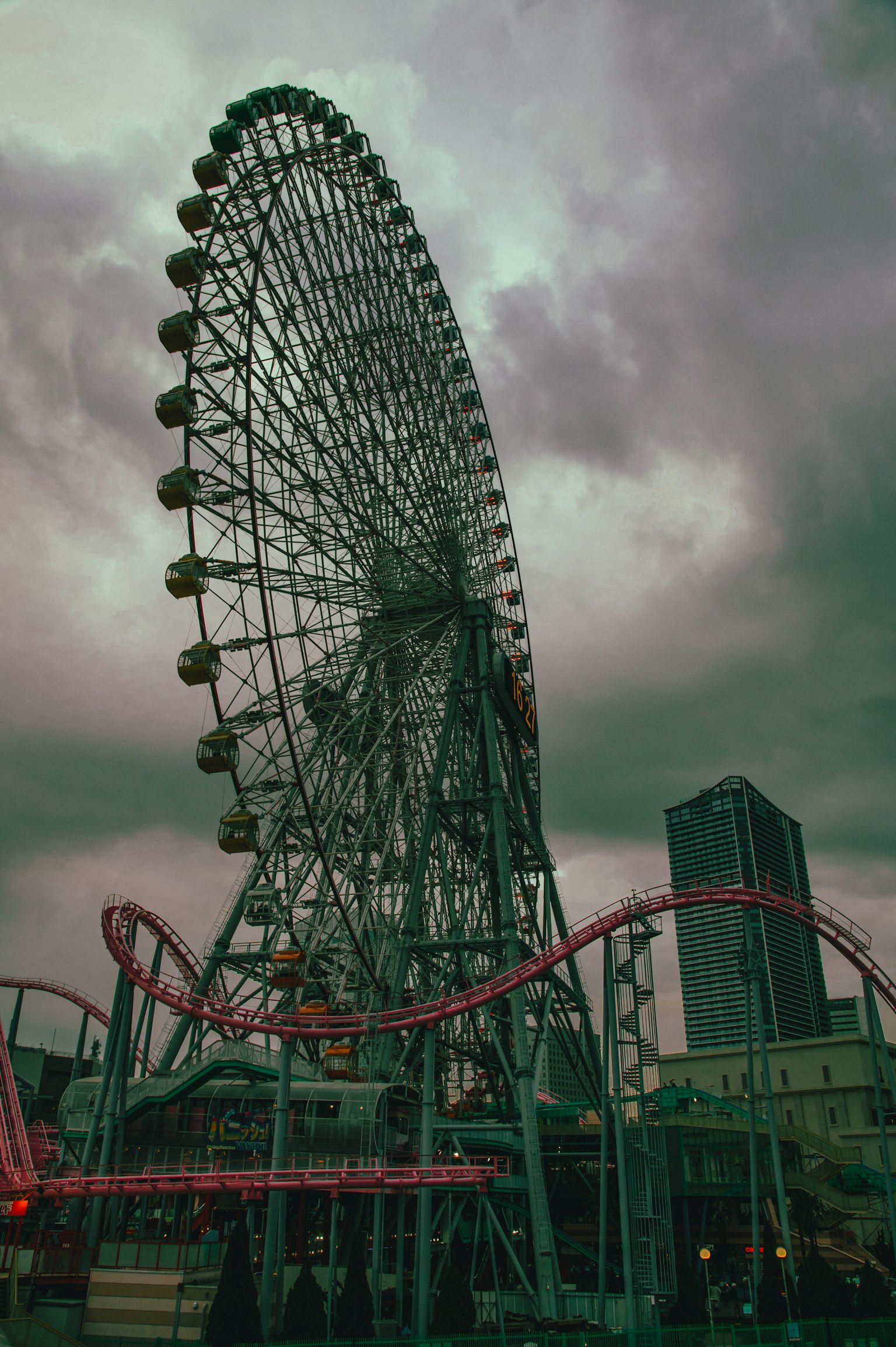 Rueda de la fortuna y montaña rusa en un parque de atracciones bajo un cielo nublado