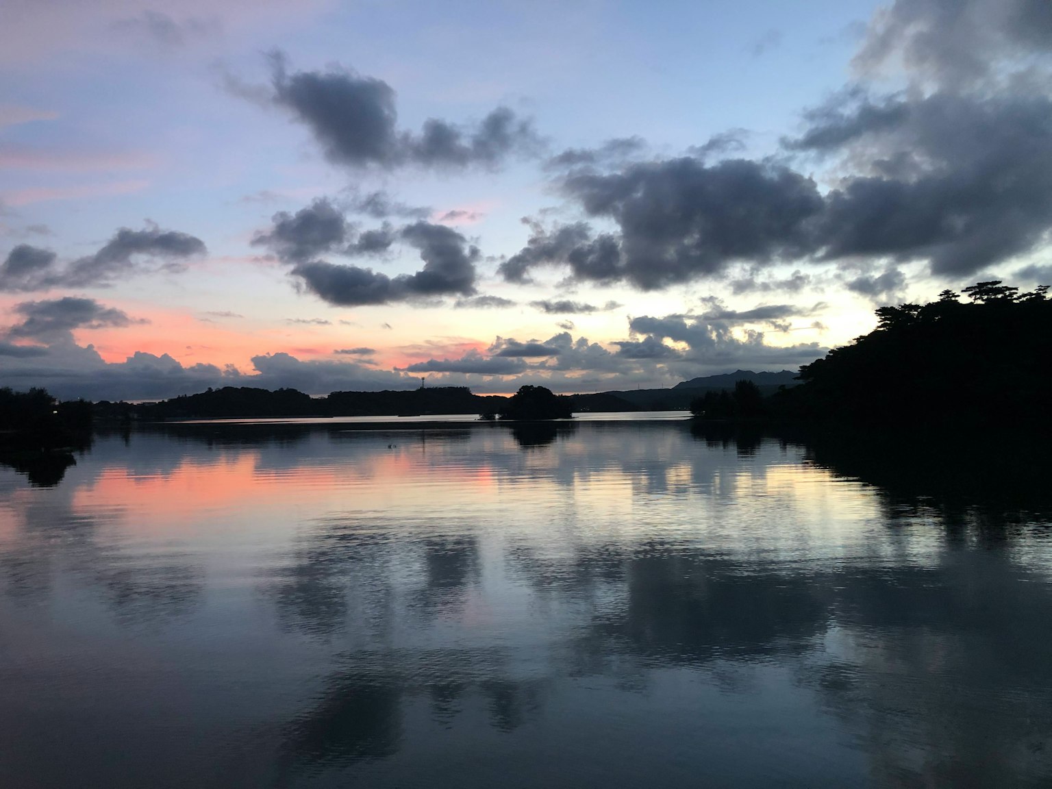 Lago sereno reflejando una hermosa puesta de sol y nubes