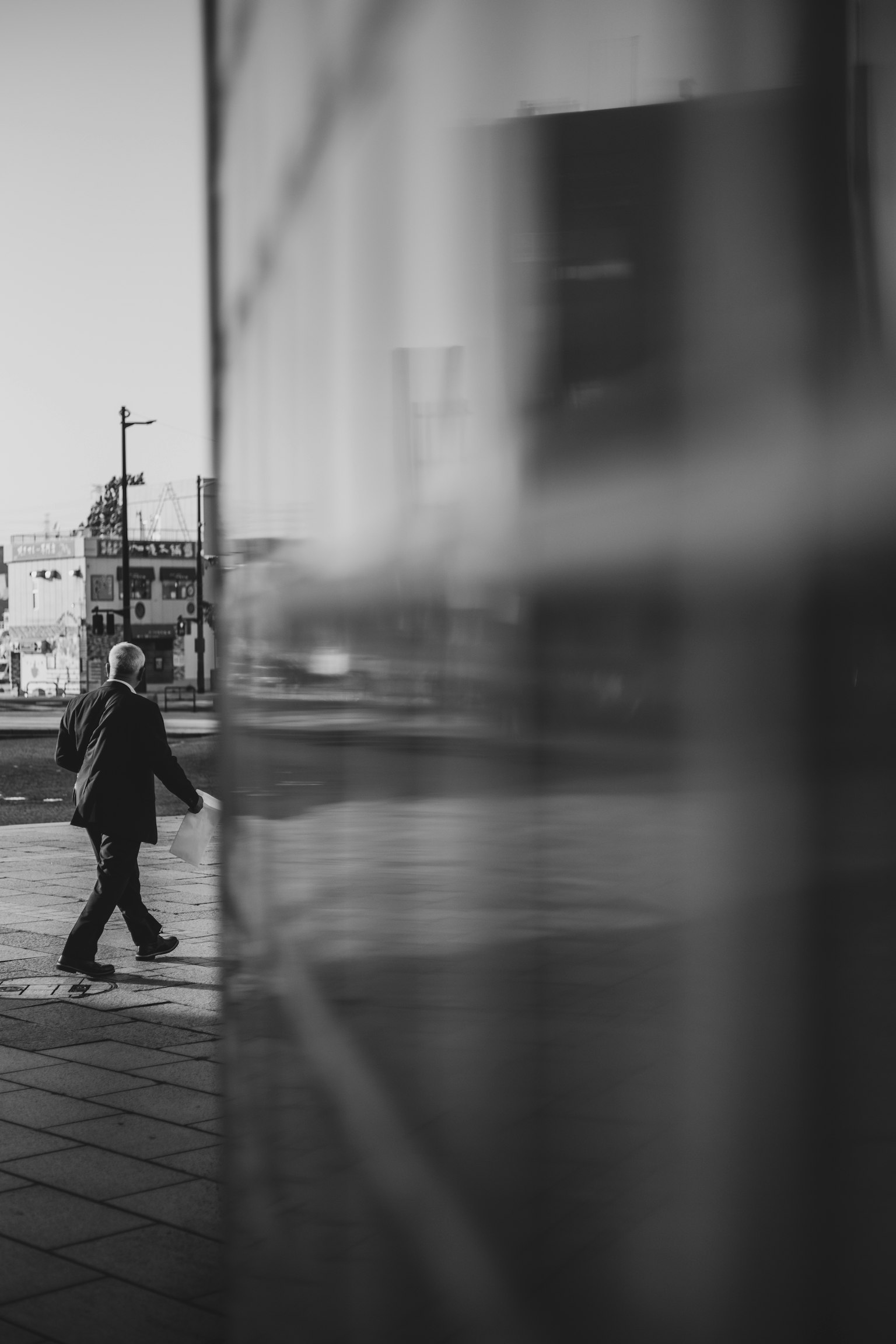 Silhouette d'un homme marchant dans une ville reflétée sur une surface en verre