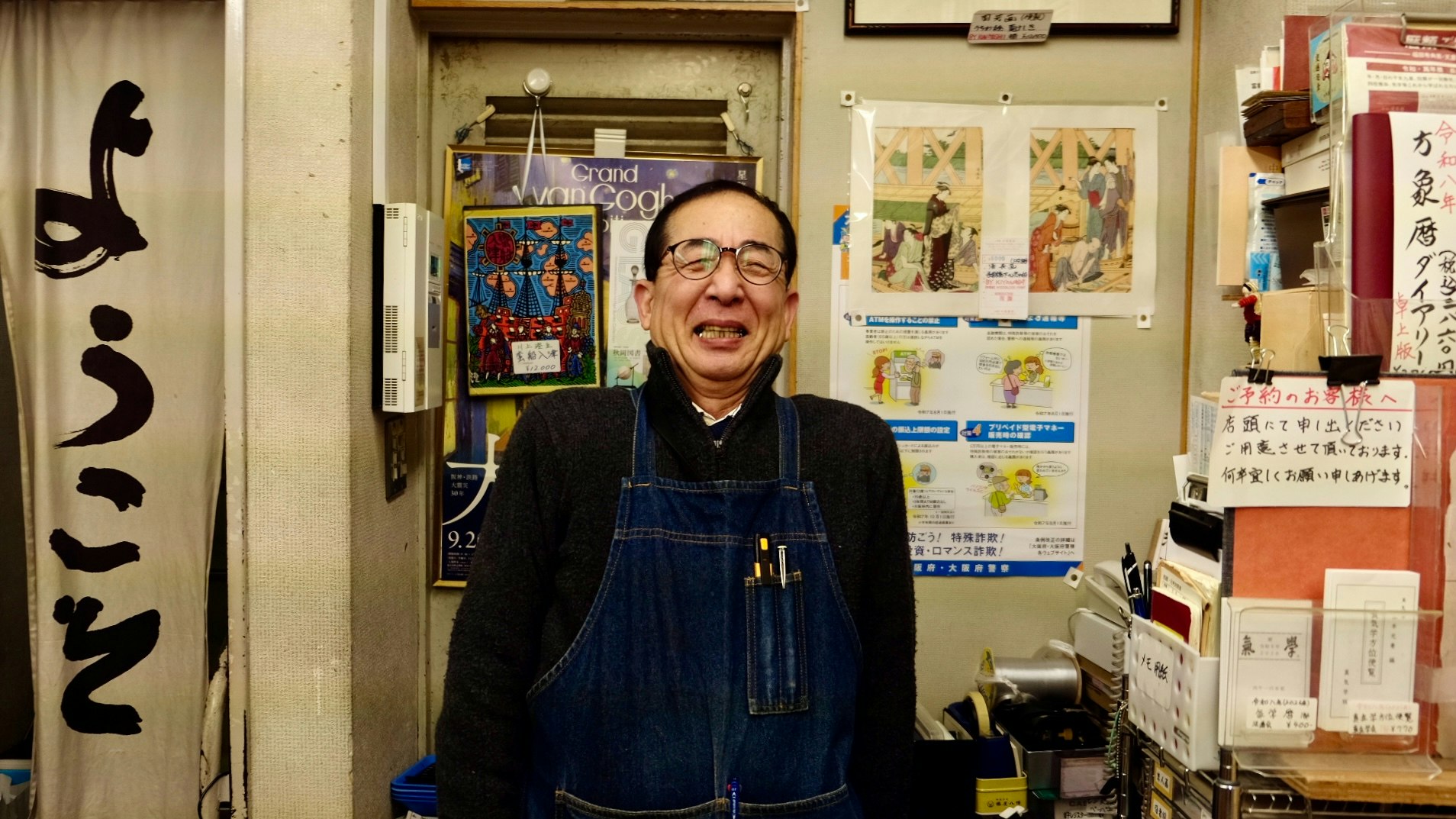 路地の小さな店内でアートを楽しむ店主の笑顔