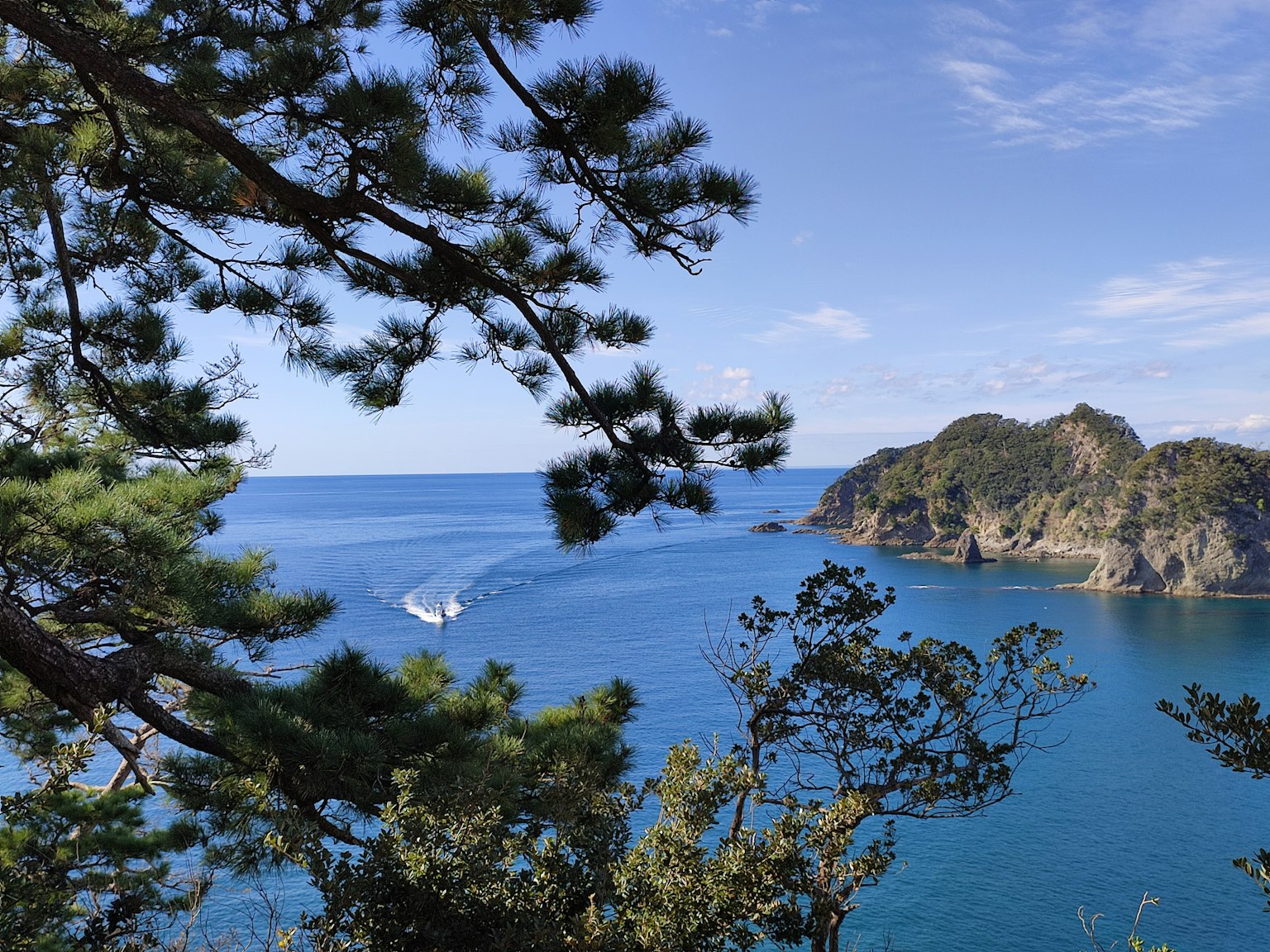 Pemandangan laut biru dengan pulau dan perahu berlayar