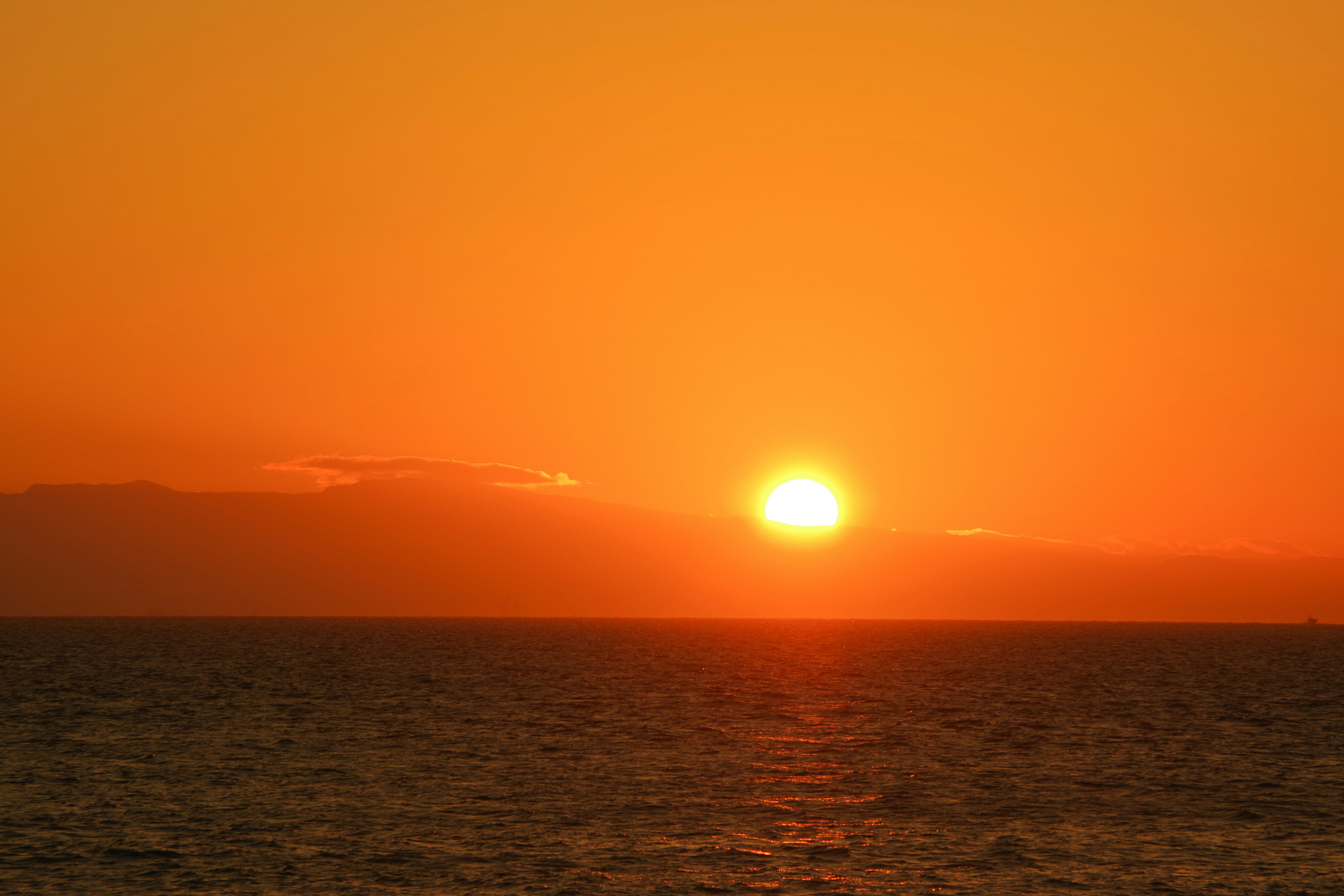 夕日に照らされる海面と水平線の風景