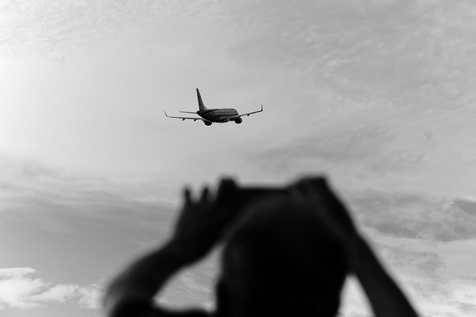 Silhouette di una persona che fotografa un aereo nel cielo