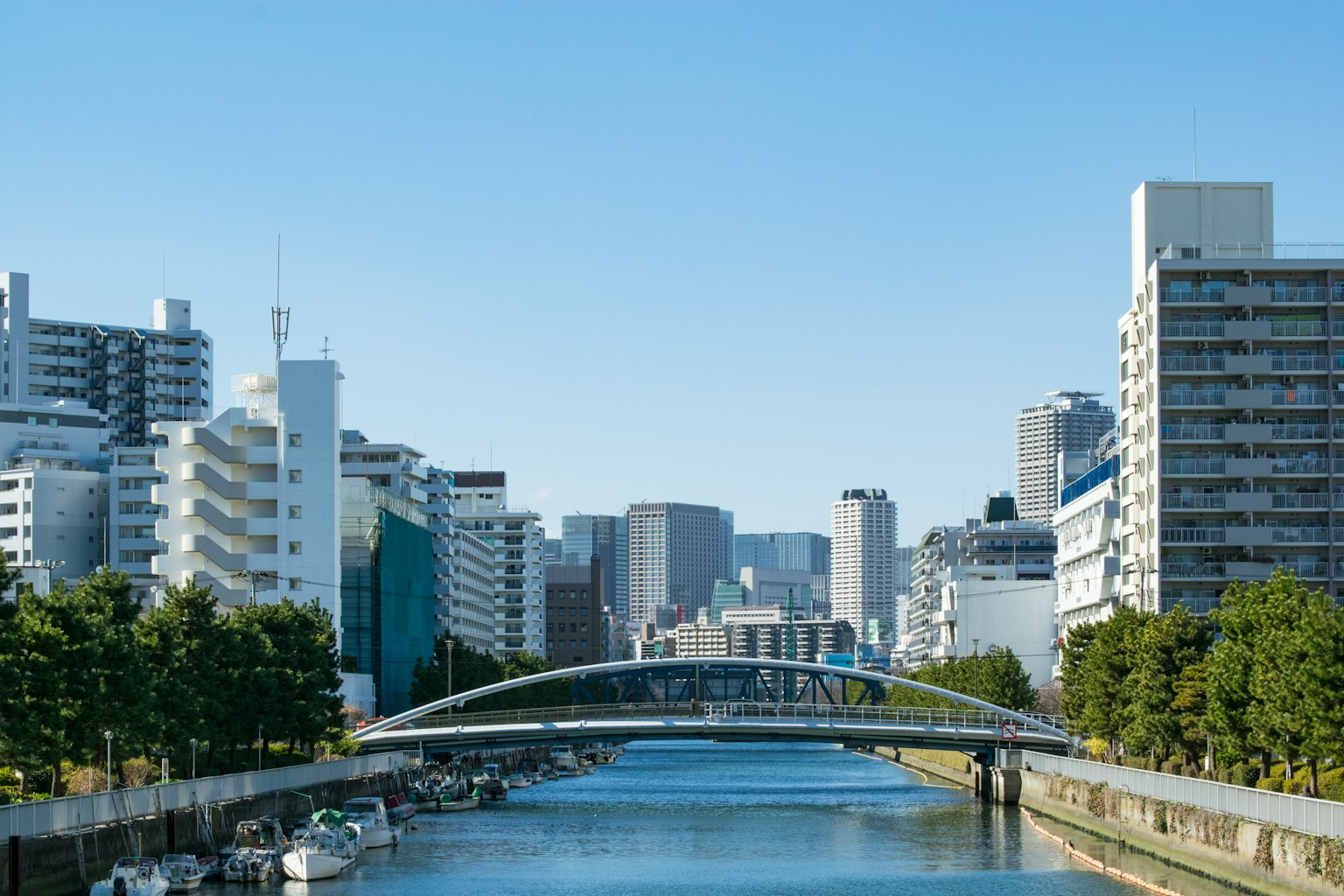 Urban landscape with a river and a bridge under a clear blue sky