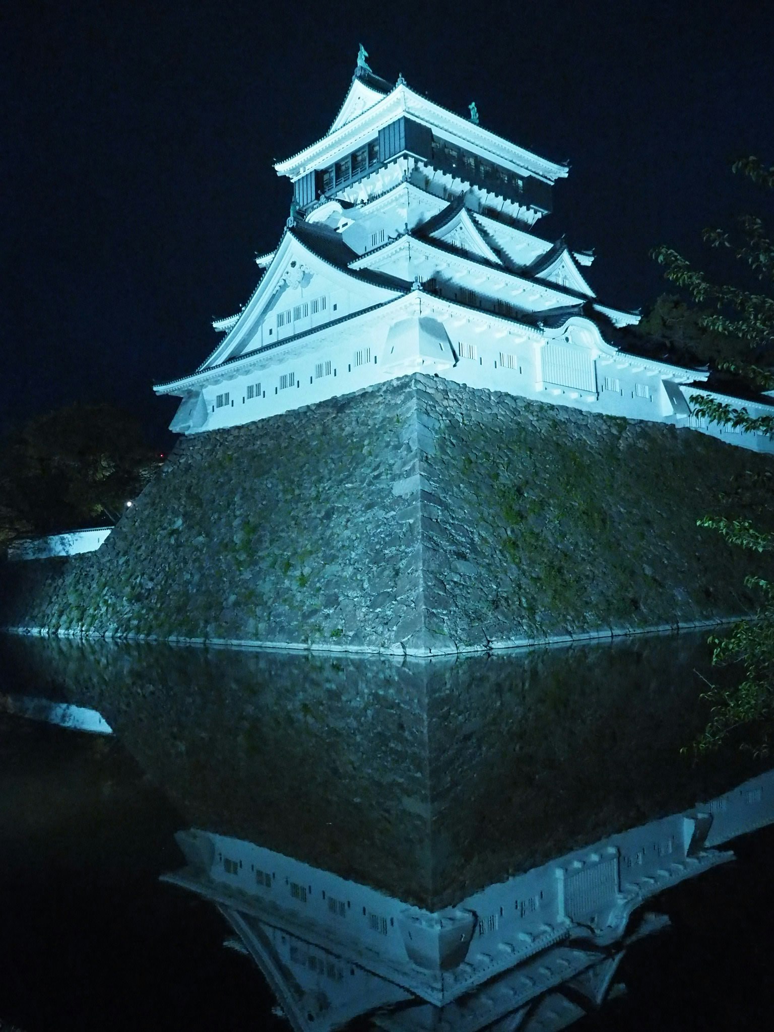 夜間照亮的白色城堡及其在水中的倒影