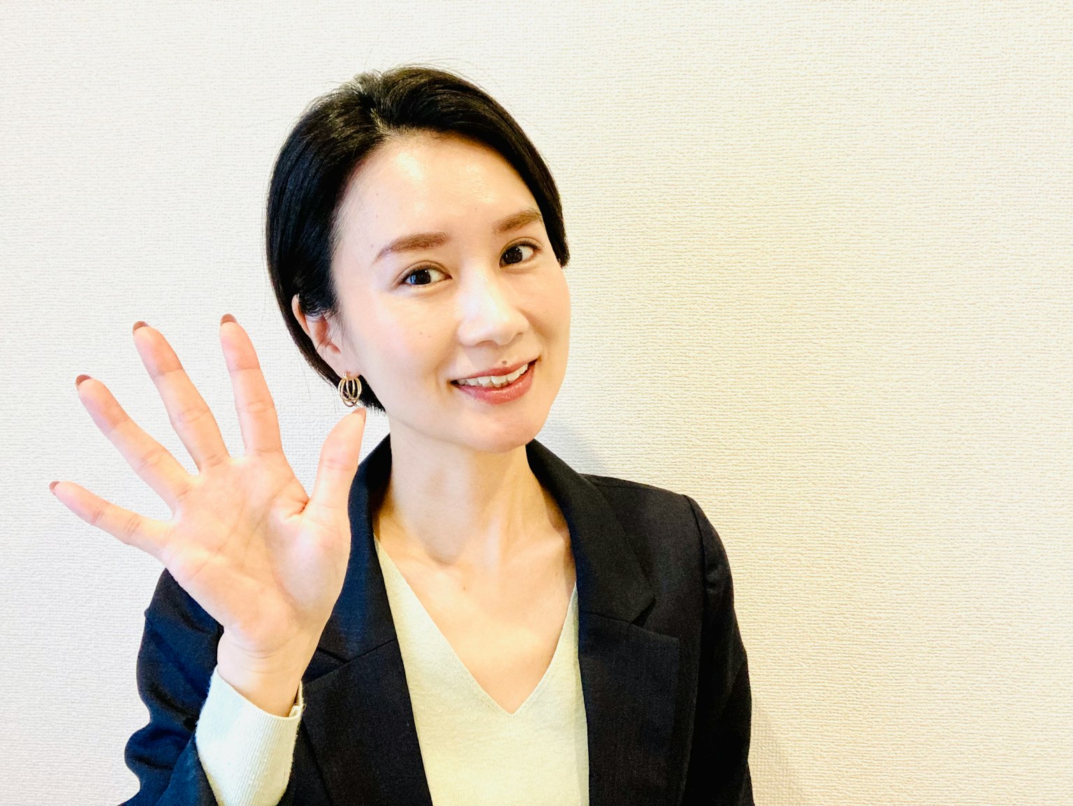一位穿著商務服裝的女性面帶微笑地揮手