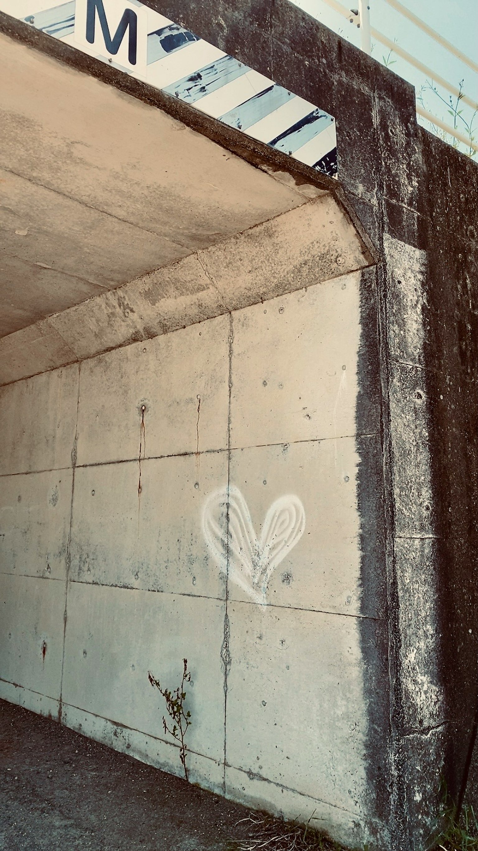 Hình vẽ graffiti hình trái tim trên tường bê tông với chữ M phía trên