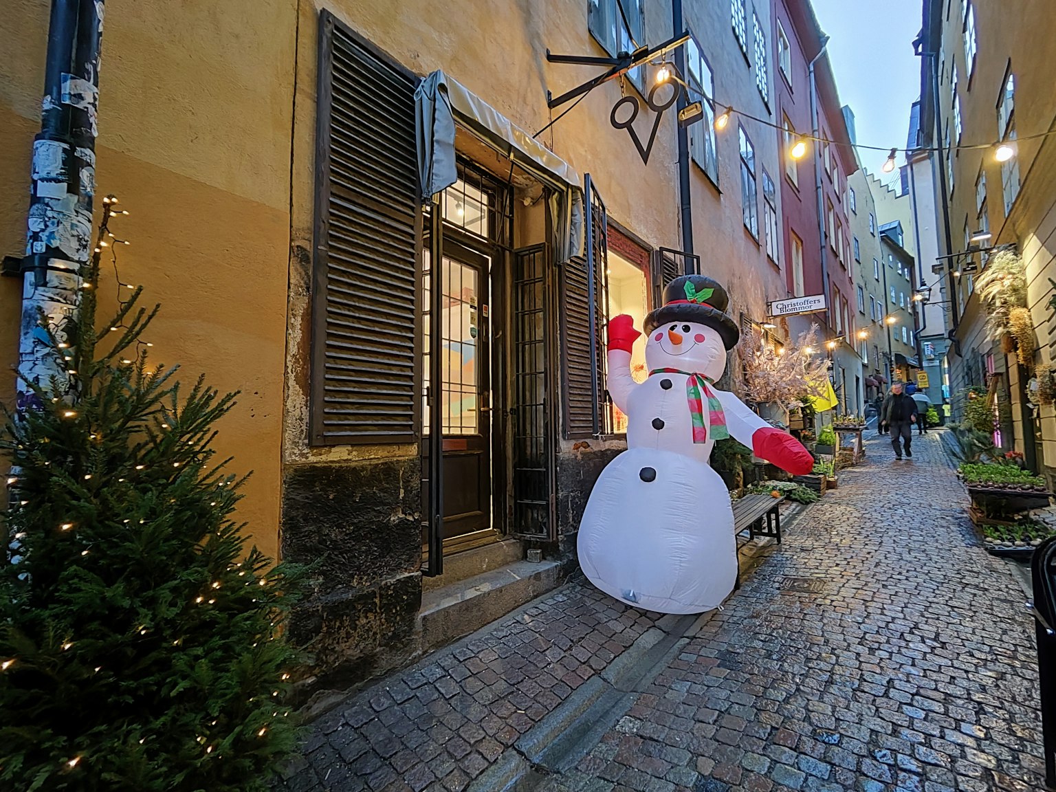 Großer Schneemann in einer für Weihnachten dekorierten Kopfsteinpflastergasse