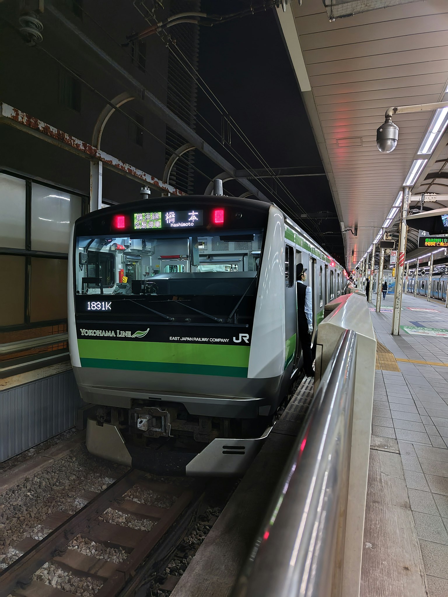 Treno JR fermo in stazione con segnaletica visibile