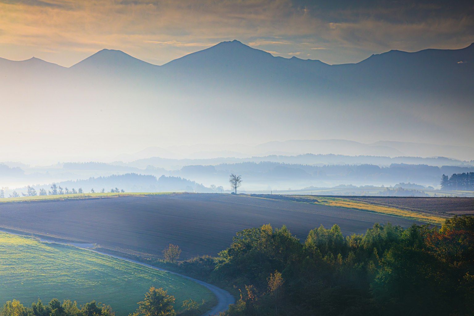 Beau paysage avec des montagnes brumeuses et des terres agricoles étendues