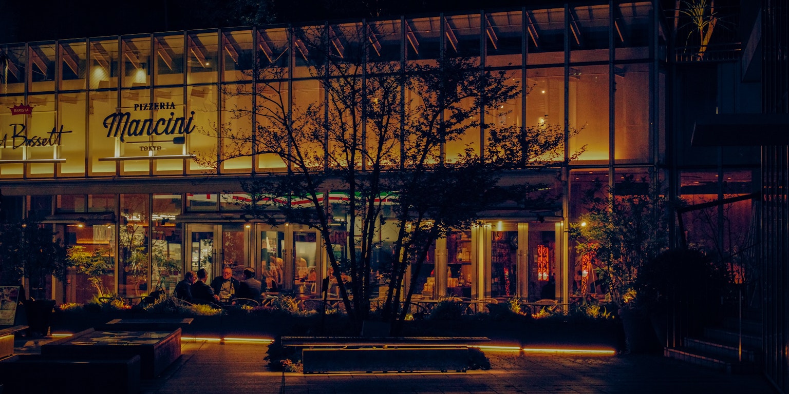 夜間照亮的現代建築外觀,周圍有植物