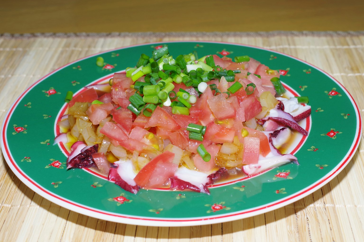 Colorful salad on a green plate featuring diced tomatoes and onions