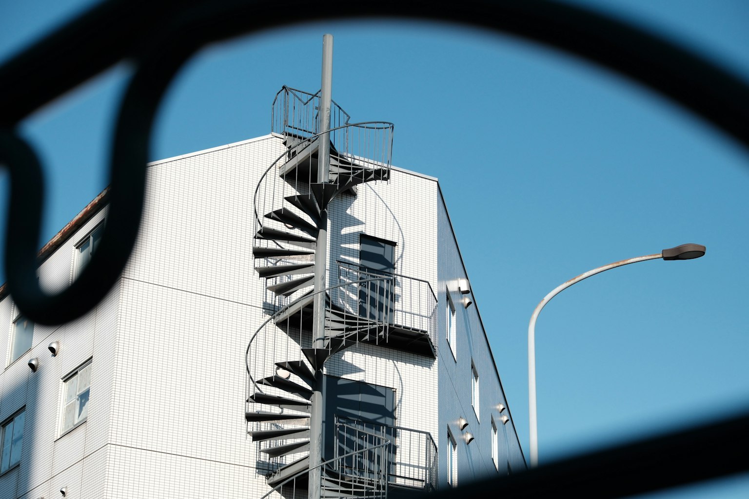 Extérieur d'un bâtiment blanc avec un escalier en colimaçon sur fond de ciel bleu