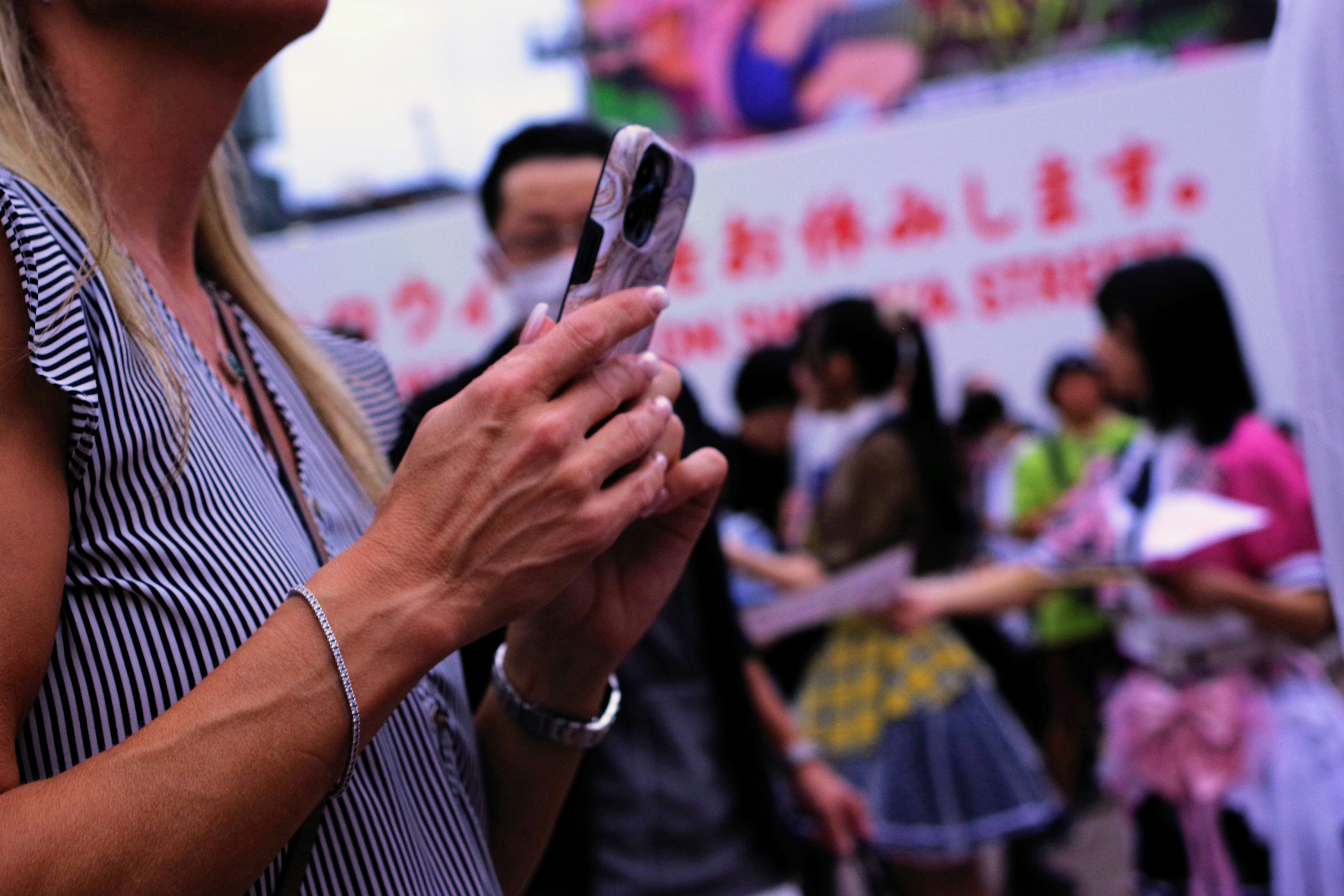 Street-style event scene with a person holding a smartphone