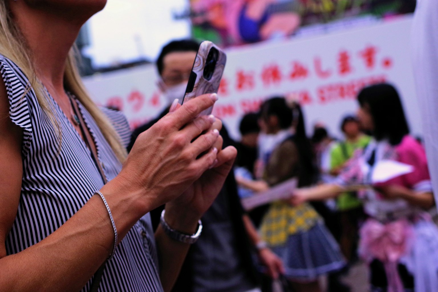 A woman holding a smartphone with a crowd of people in the background