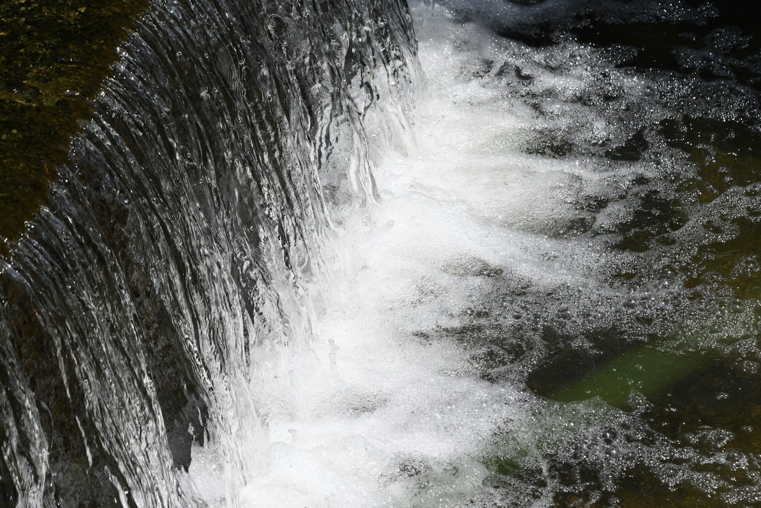 流動的瀑布白色泡沫在岩石上流淌綠色水面