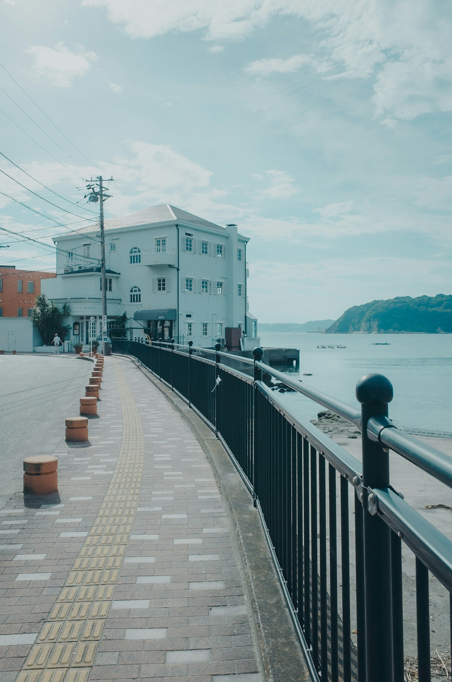 海沿いの遊歩道とフェンス、遠景の岬
