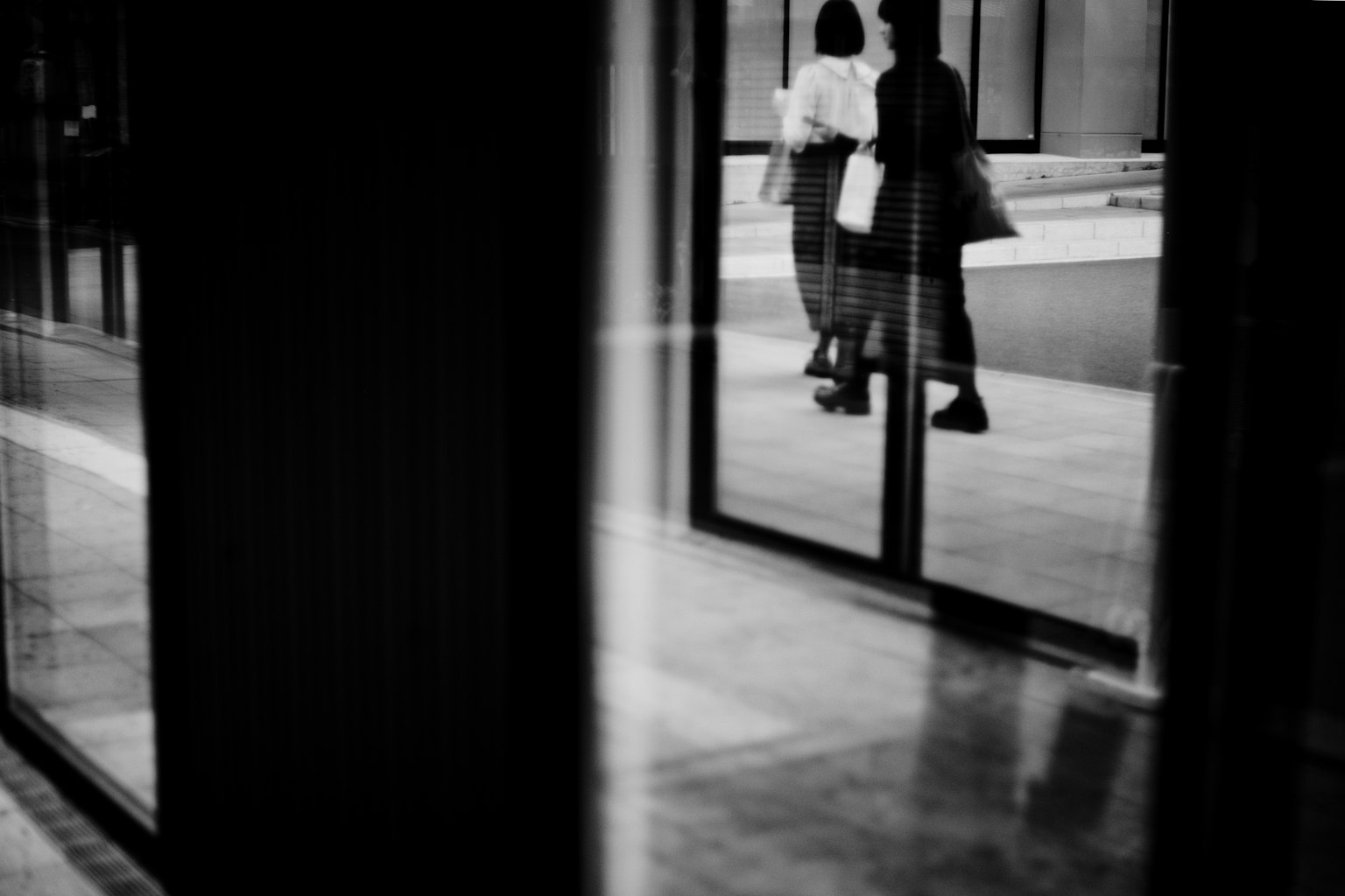 Silhouette di due persone che camminano attraverso un riflesso di vetro