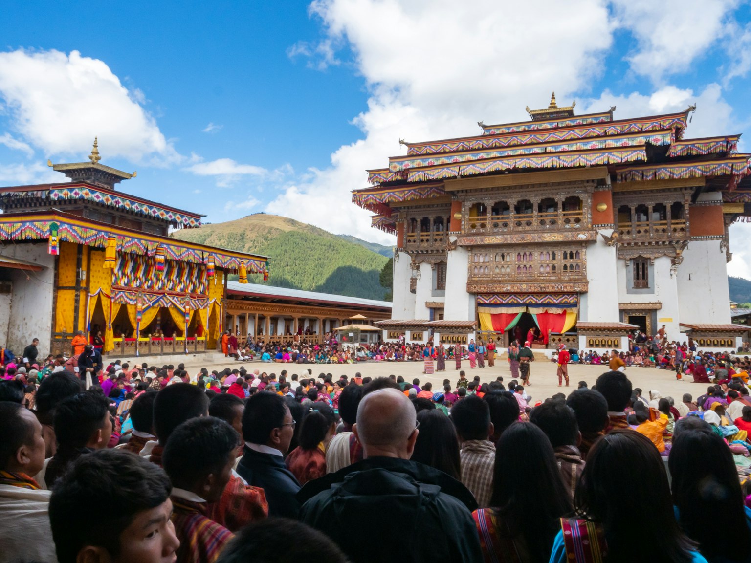 Foule rassemblée lors d'un festival bhoutanais traditionnel avec une belle architecture de temple