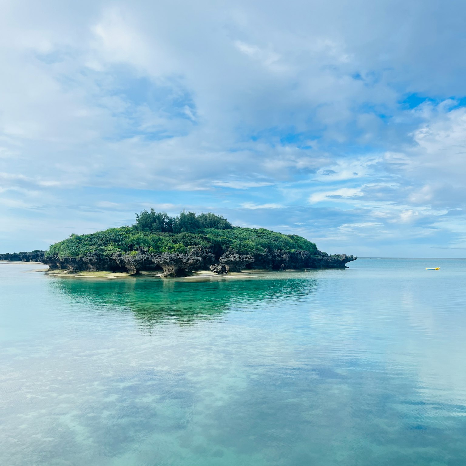 Pulau kecil di laut tenang dengan langit biru