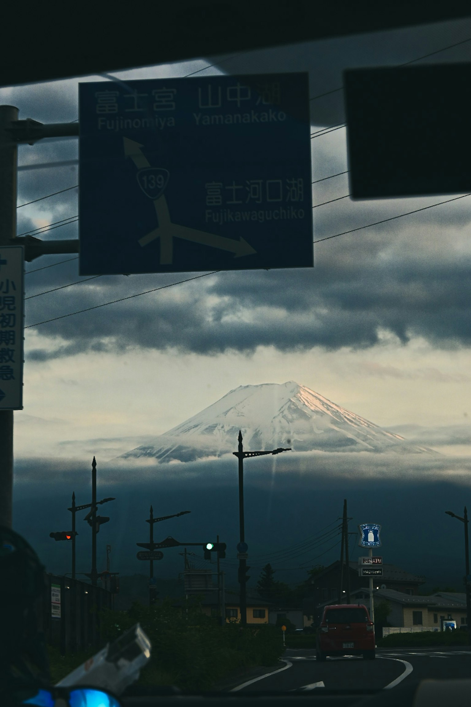 View of Mount Fuji partially visible through clouds with road signs