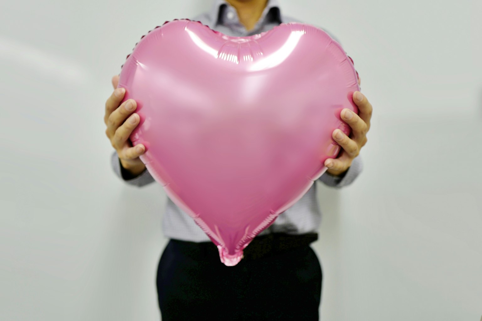 Pria memegang balon berbentuk hati berwarna pink