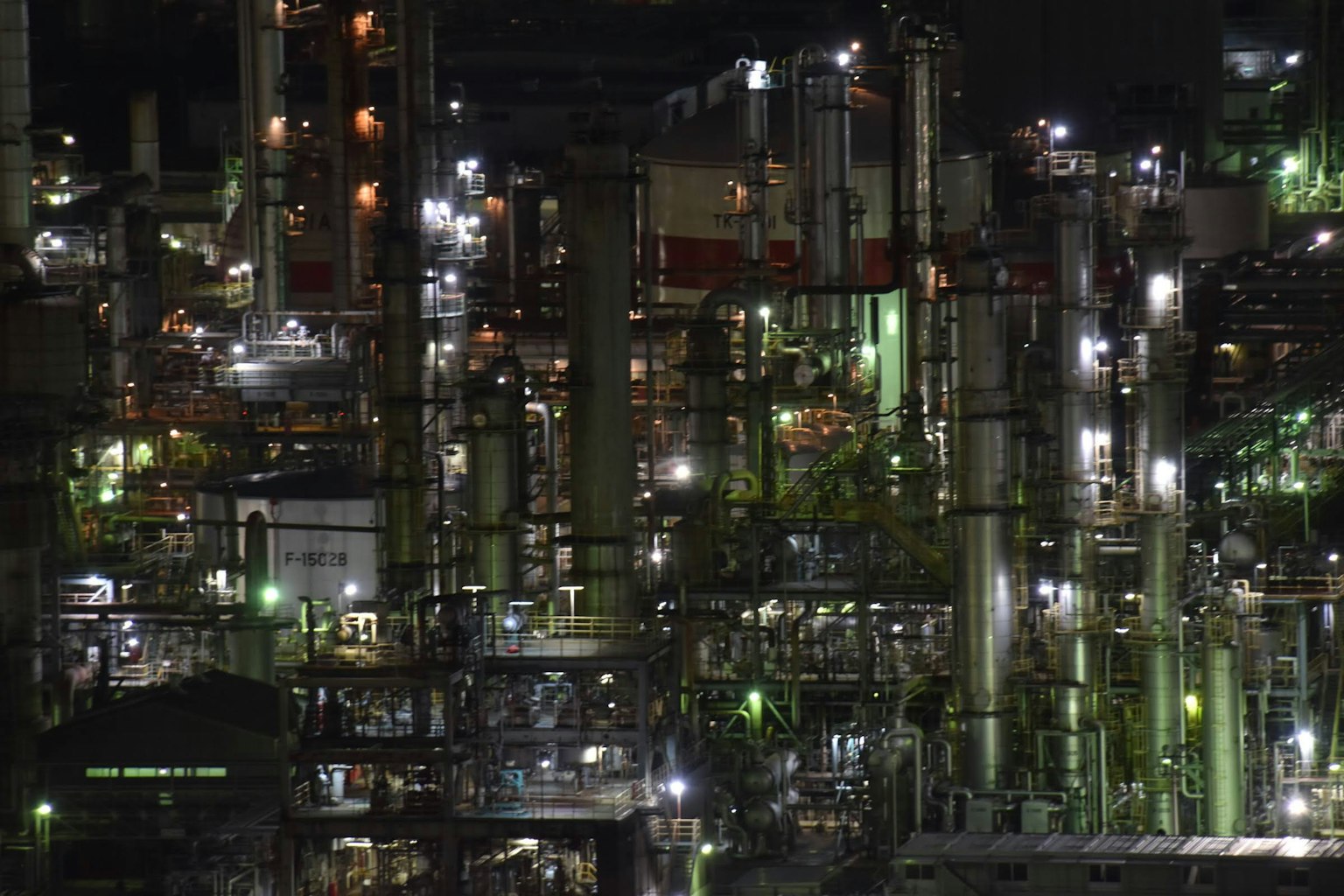 Complex arrangement of pipes and tanks illuminated at night in a factory