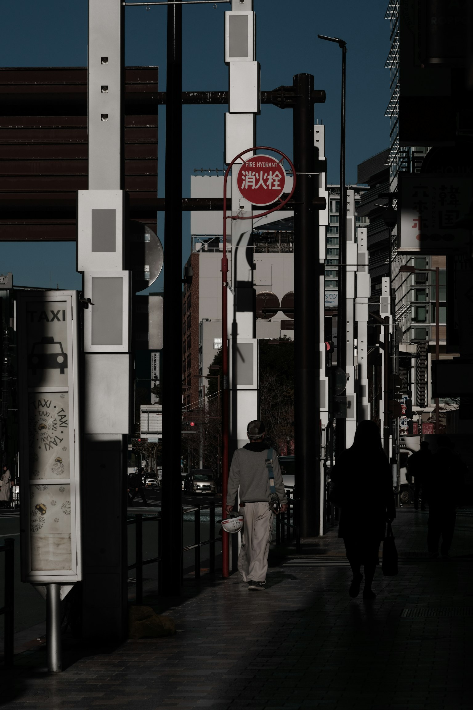 城市街道场景，阴影中的行人和交通标志