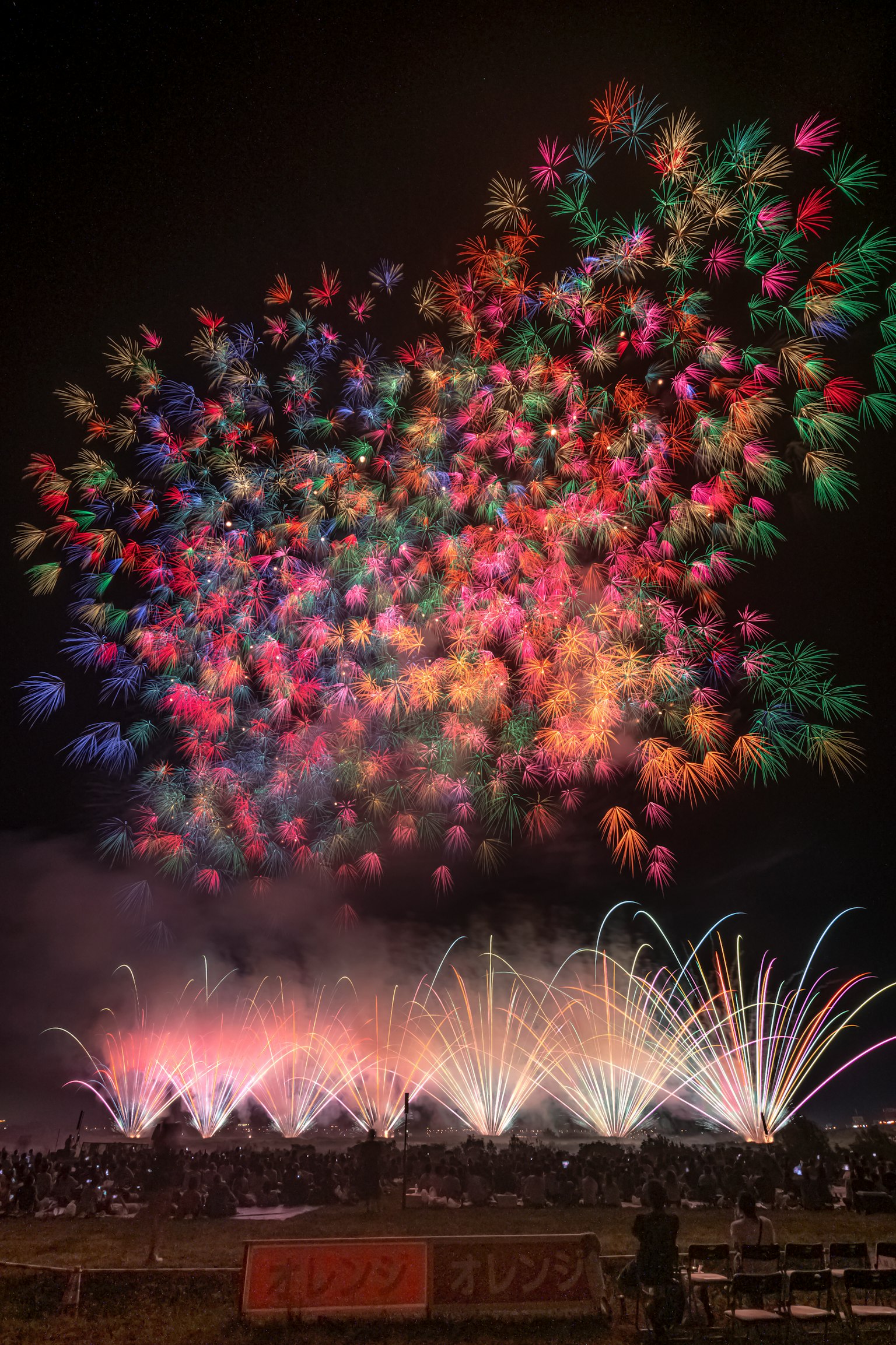 Fuochi d'artificio colorati che esplodono nel cielo notturno con fontane d'acqua sottostanti
