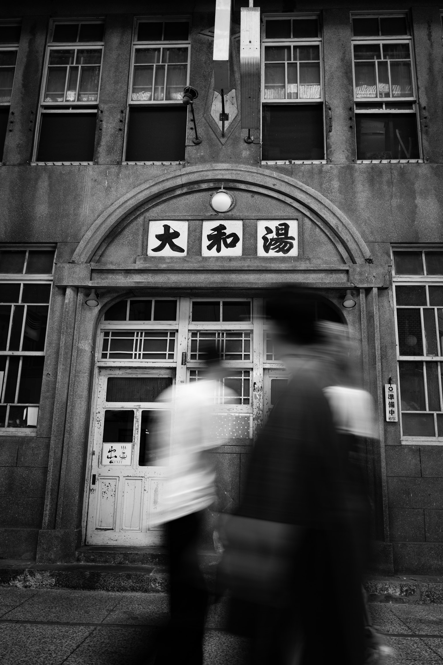 人们走过一栋黑白老建筑，标有大和汤的招牌