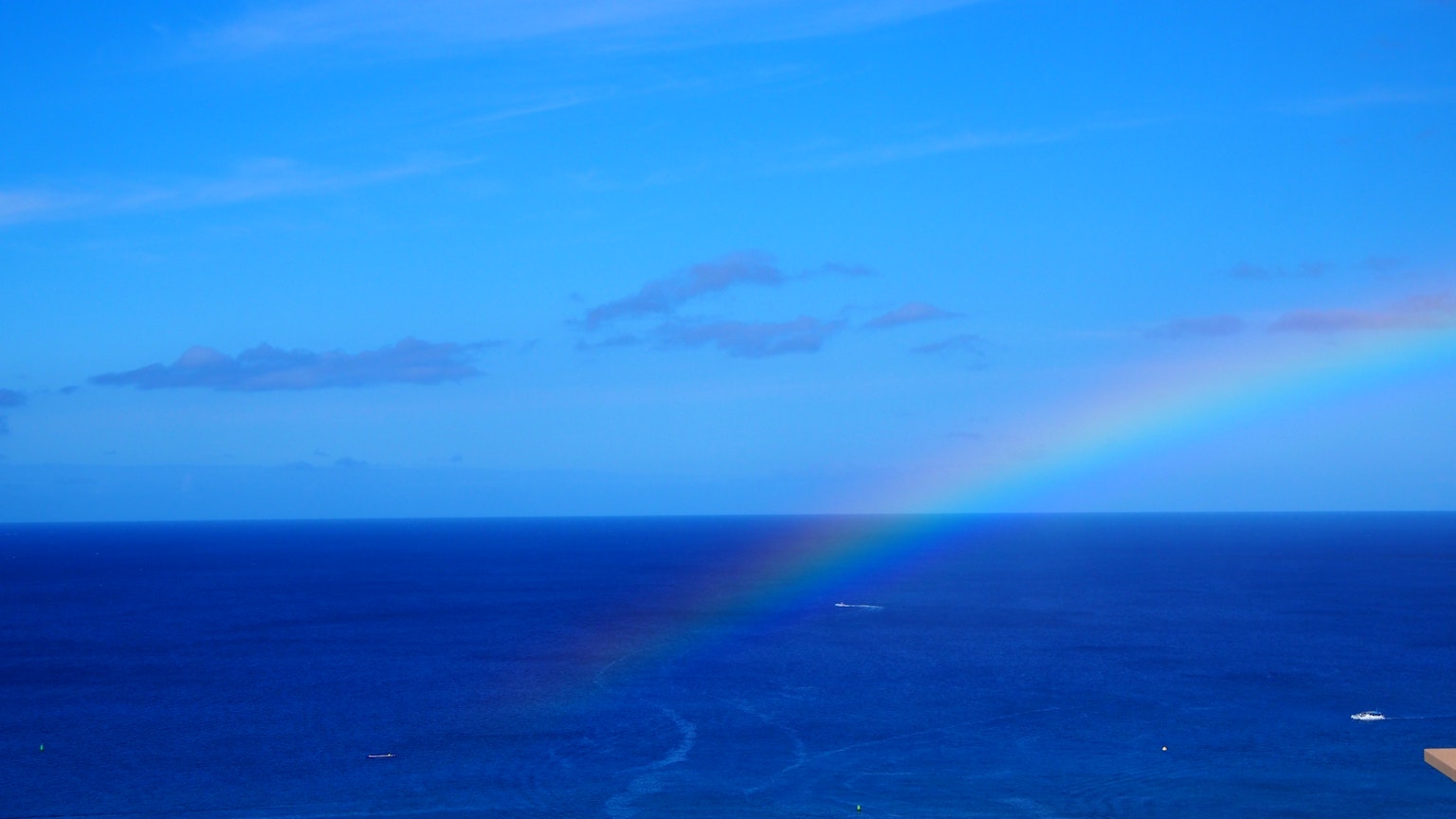 A beautiful scene of a rainbow in the blue sky and ocean