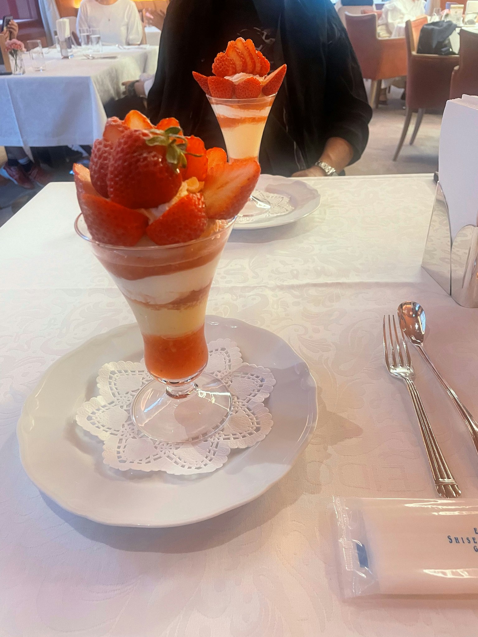 Parfait di fragole su un tavolo con strati di crema e fragole fresche disposte in modo elegante