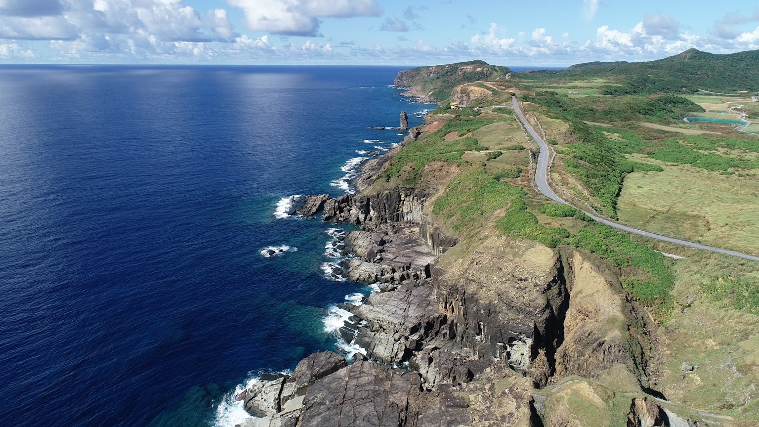 Beautiful coastal landscape with blue ocean green hills and visible road