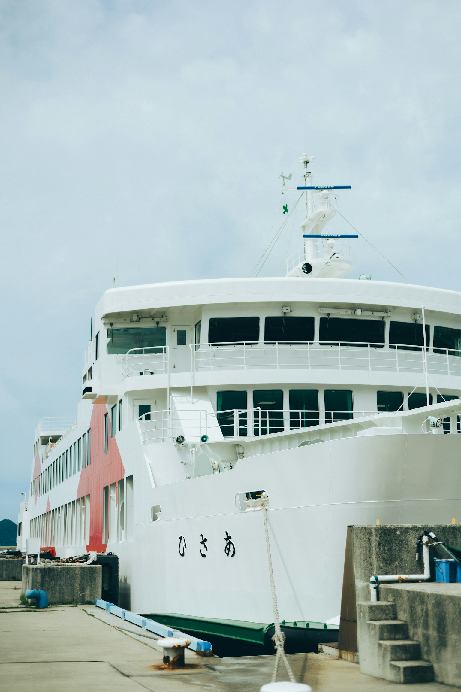 Un ferry blanc amarré au quai sous un ciel nuageux
