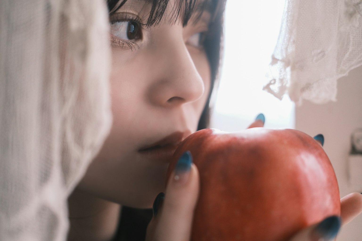 女性が赤いリンゴを持ち、思索にふけっている様子