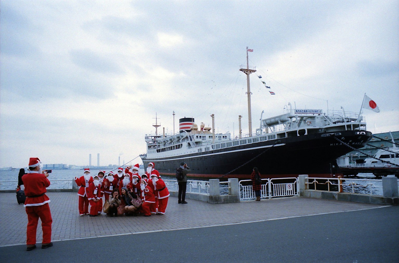 Group of people in Santa Claus costumes gathered in front of a ship