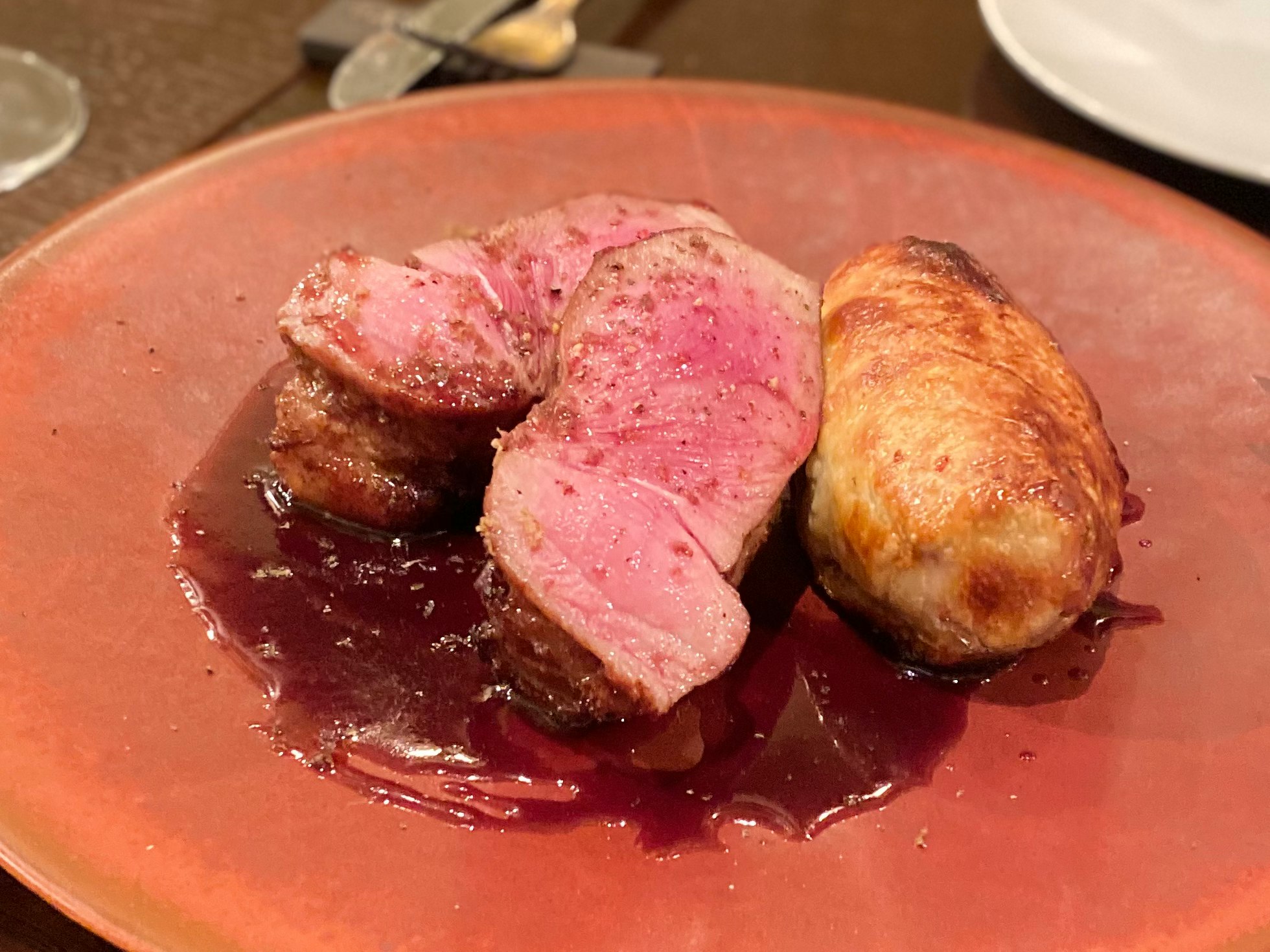 赤い皿に盛られたロースト肉とソーセージ