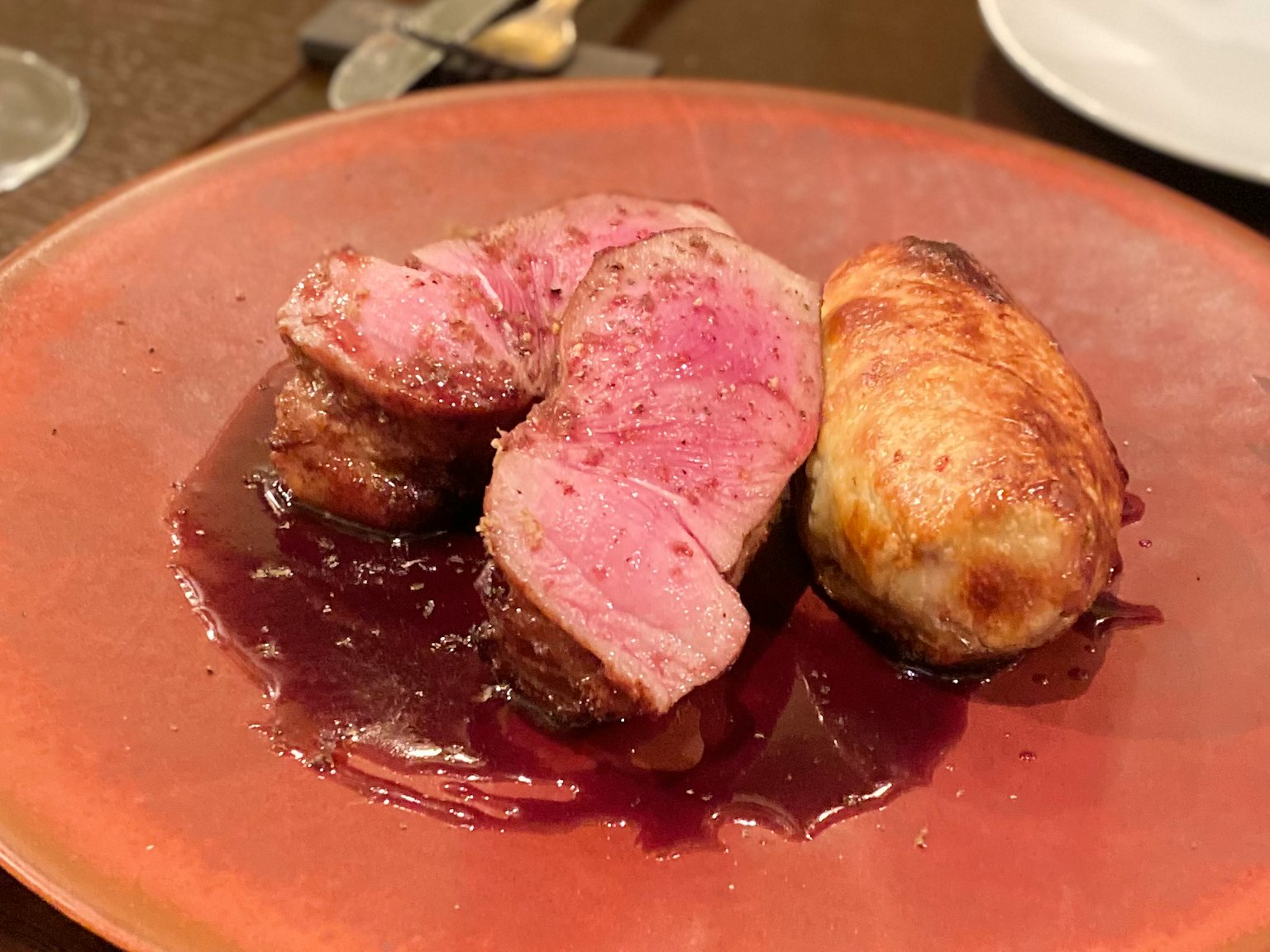 Fette di carne d'anatra con un piatto di patate servito su un piatto rosso